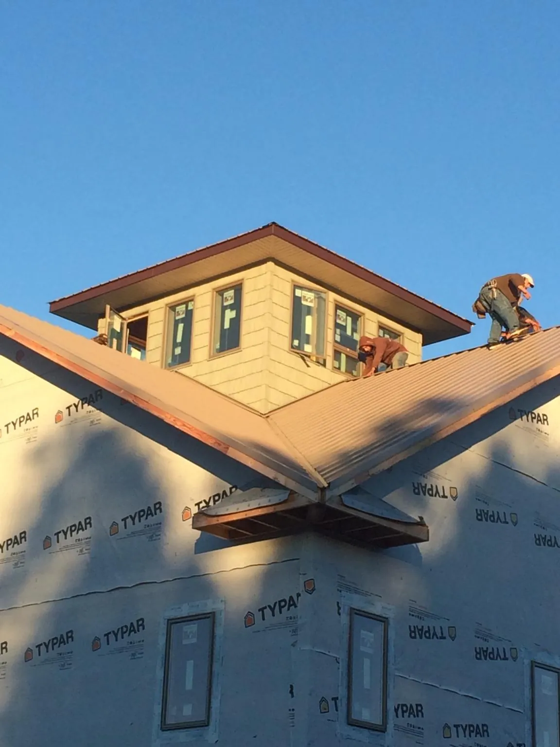 Roofers working around a rooftop cupola on a new metal roof at sunset — Roof Waterproofing in Niles by Roofing Brothers